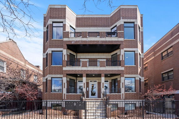 Front view of a multi-story brick residential building with balconies.