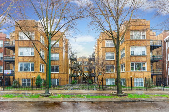 Front view of multi-story brick apartment buildings with multiple windows and metal balconies.