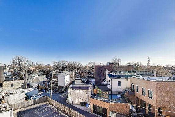 Panoramic view of urban rooftops and surrounding residential buildings with a clear blue sky.