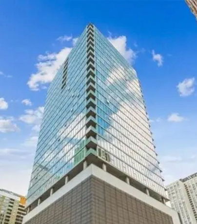 Front view of a tall glass-facade skyscraper.