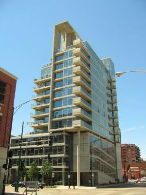 Front view of a multi-story building with glass facade and balconies.