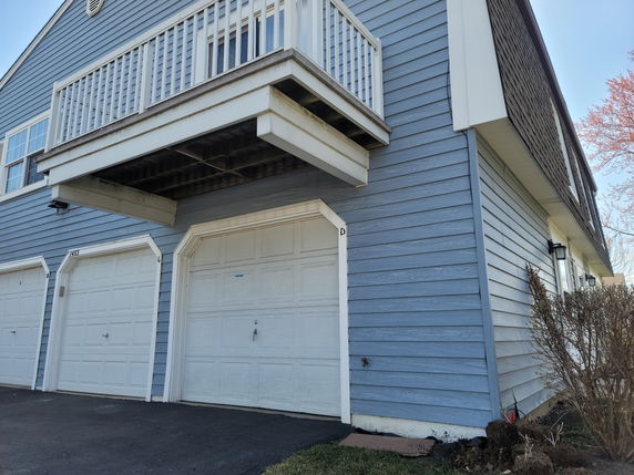 Front view of a house with a balcony and multiple garage doors.