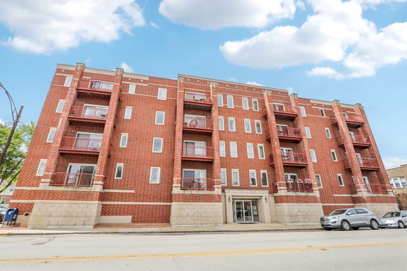 Front view of a multi-story brick apartment building with balconies.