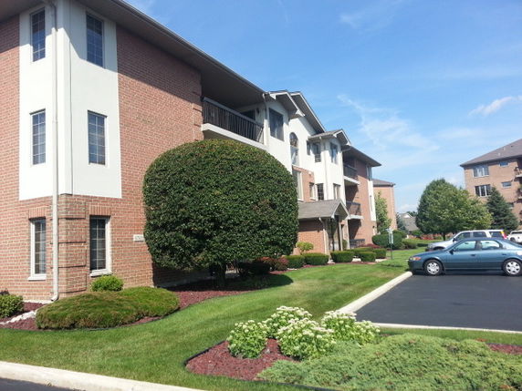 Front view of a multi-story brick apartment building with large windows.