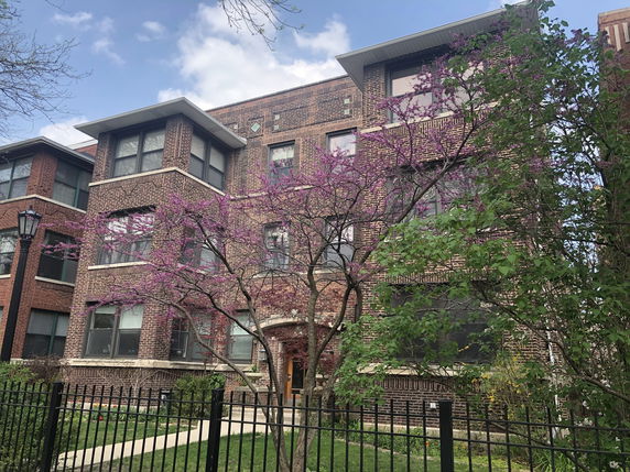 Front view of a multi-story brick building with large windows.