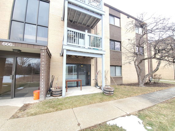 Front view of a multi-story apartment building with balconies and large windows.