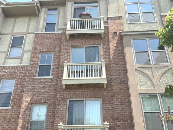 Front view of a multi-story building with brick facade and multiple balconies.