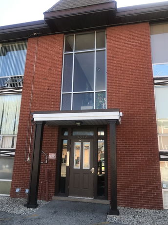 Front view of a building with a brick facade and large glass windows.