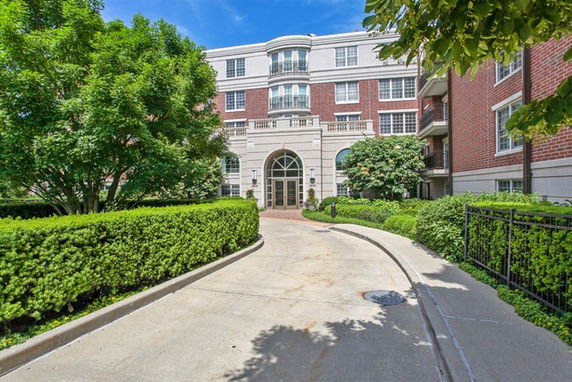 Front view of a multi-story brick apartment building with an arched entrance.