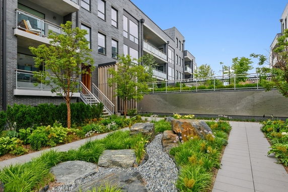 Front view of a multi-story apartment building with balconies and landscaped garden.