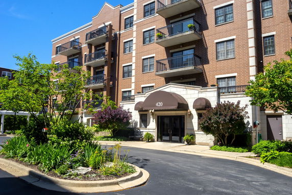 Front view of a multi-story apartment building with balconies and an entrance canopy.