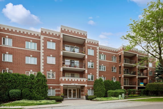 Front view of a four-story brick apartment building with balconies.