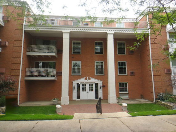 Front view of a multi-story brick building with balconies and a central entrance.