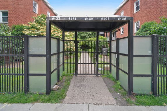 Front view of a gated entrance to a red brick apartment building.