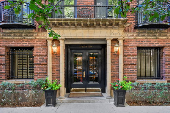 Front view of a brick building entrance with ornate columns and lanterns.