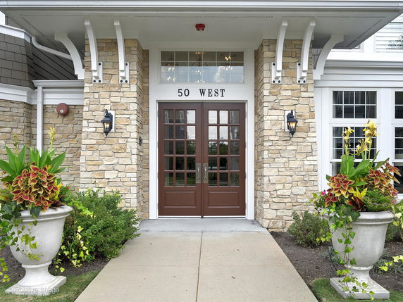 Front view of a building entrance with stone facade and brown double doors.