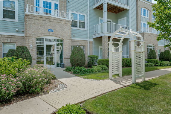 Front view of a multi-story residential building with balconies and a brick facade.