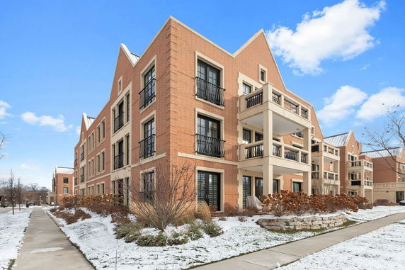 Front view of a three-story brick apartment building with balconies.