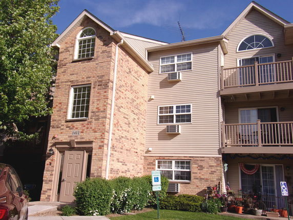 Front view of a multi-story residential building with brick facade and balconies.