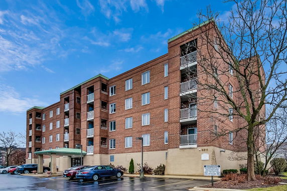 Front view of a multi-story brick apartment building with balconies.