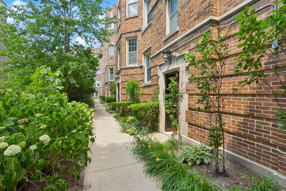 Front view of a brick residential building with entrance and windows.
