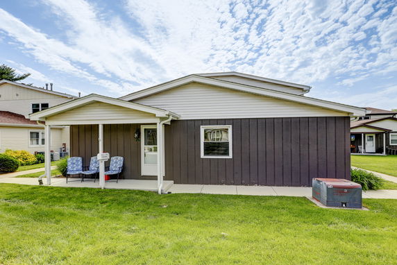 Front view of a single-story house with a porch and seating area.