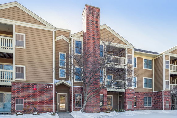 Front view of a multi-story apartment building with balconies and a brick facade.