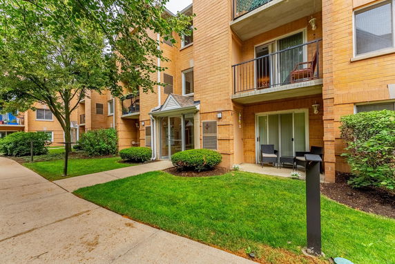 Front view of a multi-story residential building with balconies and sliding glass doors.