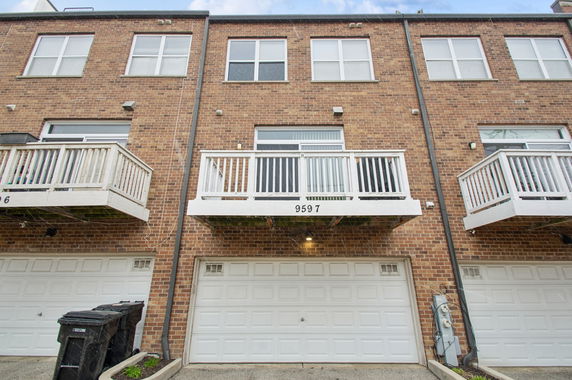 Front view of a multi-story brick townhouse with balconies and garages.