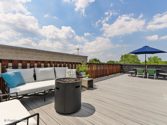 Rooftop area with seating and a table with an umbrella.