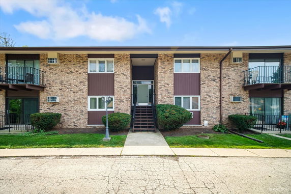 Front view of a two-story apartment building with brick and paneling exterior.