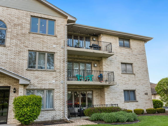 Front view of a multi-story brick apartment building with balconies.