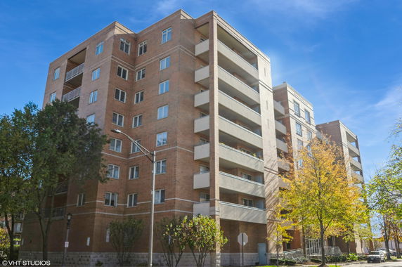 Front view of a multi-story brick apartment building with balconies.