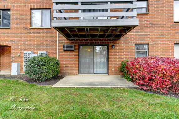 Front view of a brick building with a balcony and sliding glass door.