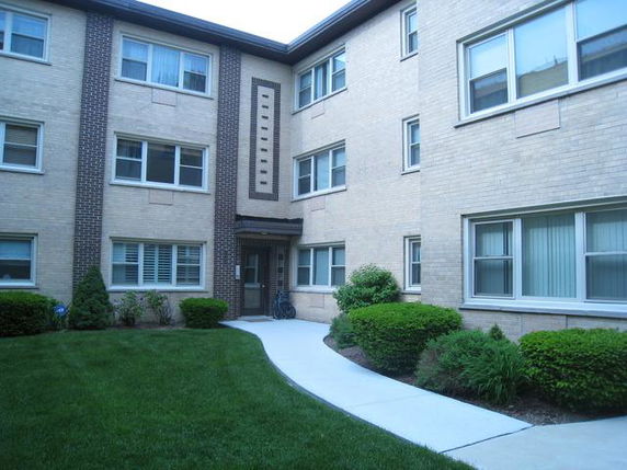 Front view of a multi-story apartment building with a central entryway.