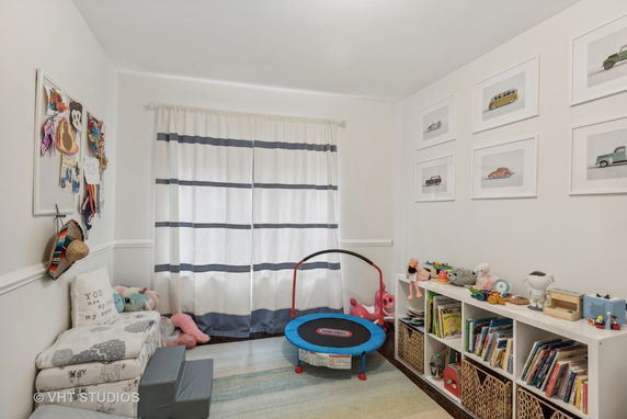 Indoor children's play area with a mini trampoline and toys organized on shelves.