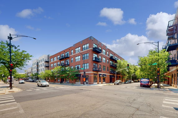 Front view of a multi-story brick apartment building on a street corner.