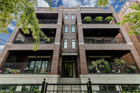 Front view of a multi-story brick building with balconies and greenery.
