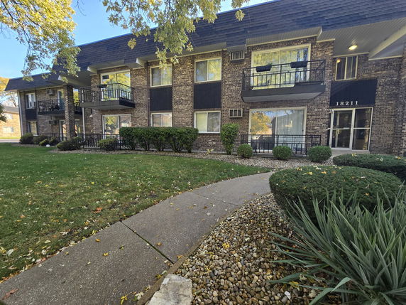 Front view of a multi-story brick apartment building with balconies.
