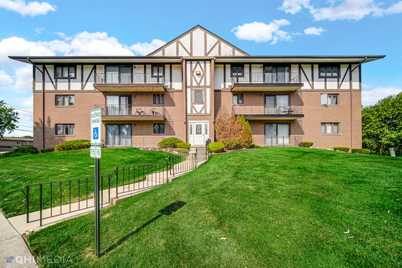 Front view of a multi-story brick apartment building with balconies.