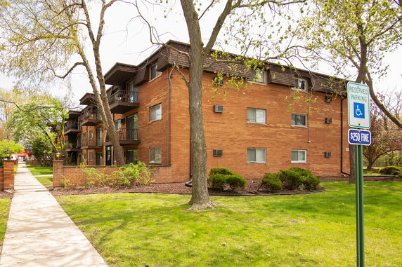 Front view of a three-story brick apartment building with balconies.