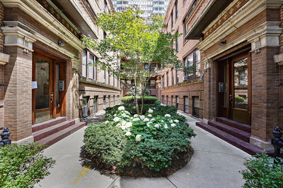 View of a brick residential building with a landscaped entrance.