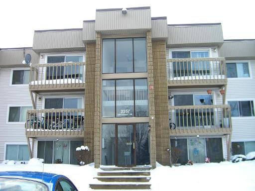 Front view of a multi-story apartment building with balconies and large windows.
