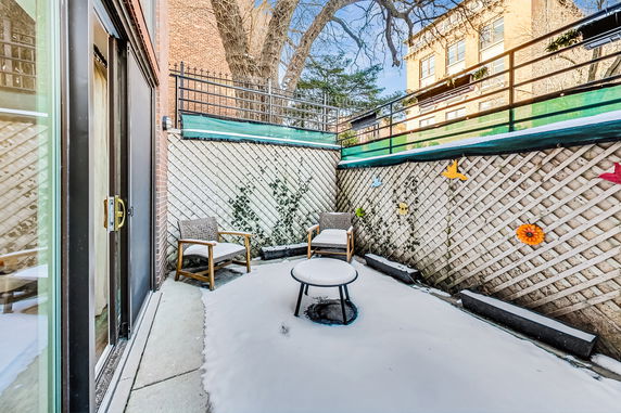 Outdoor patio area with chairs and a small table covered in snow.