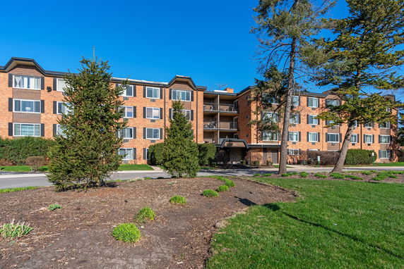 Front view of a four-story brick apartment building with balconies.