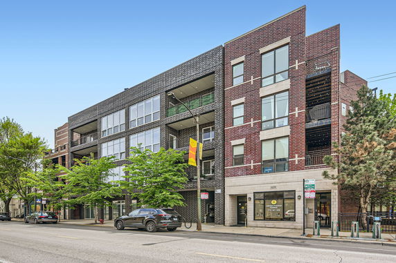 Front view of a multi-story brick building with large windows and balconies.