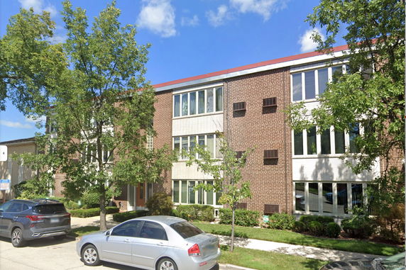 Front view of a multi-story brick building with large windows.