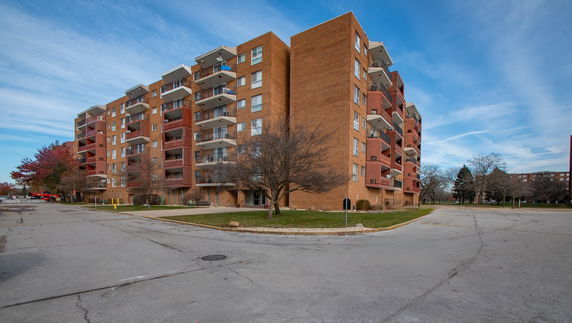 Front view of a multi-story brick apartment building with balconies.