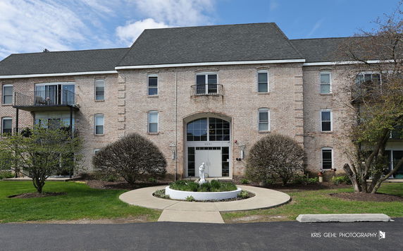 Front view of a multi-story brick building with balconies and arched entrance.
