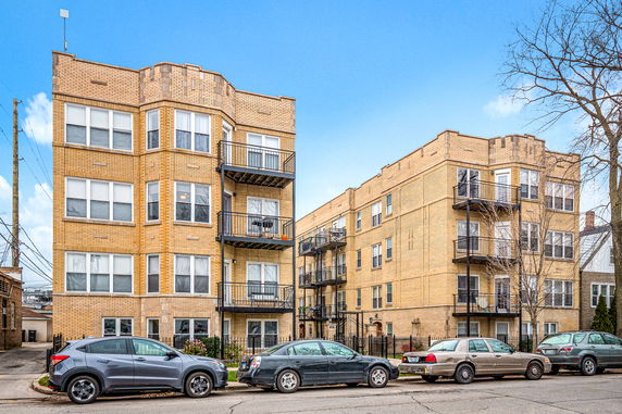 Front view of a multi-story apartment building with brick exterior and balconies.